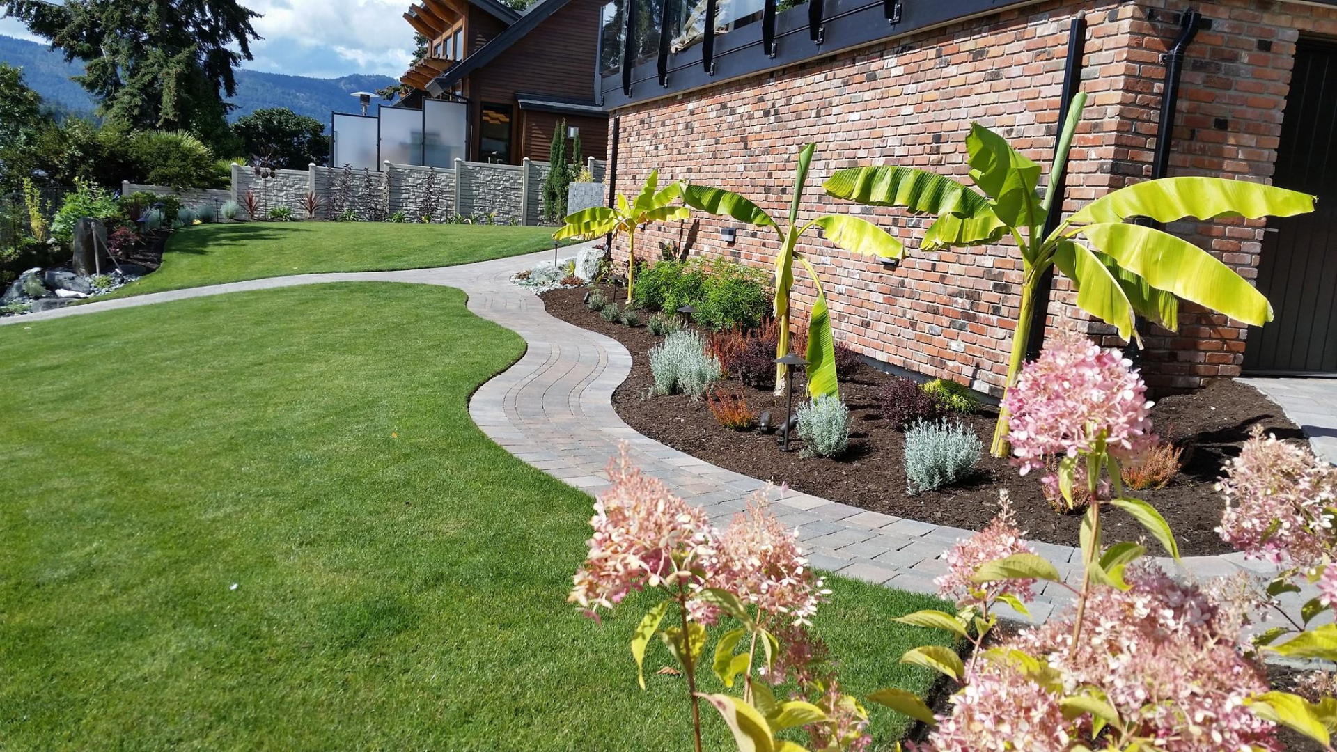 Landscaped yard in Greater Victoria with lawn, mulched garden beds, and drought-tolerant planting